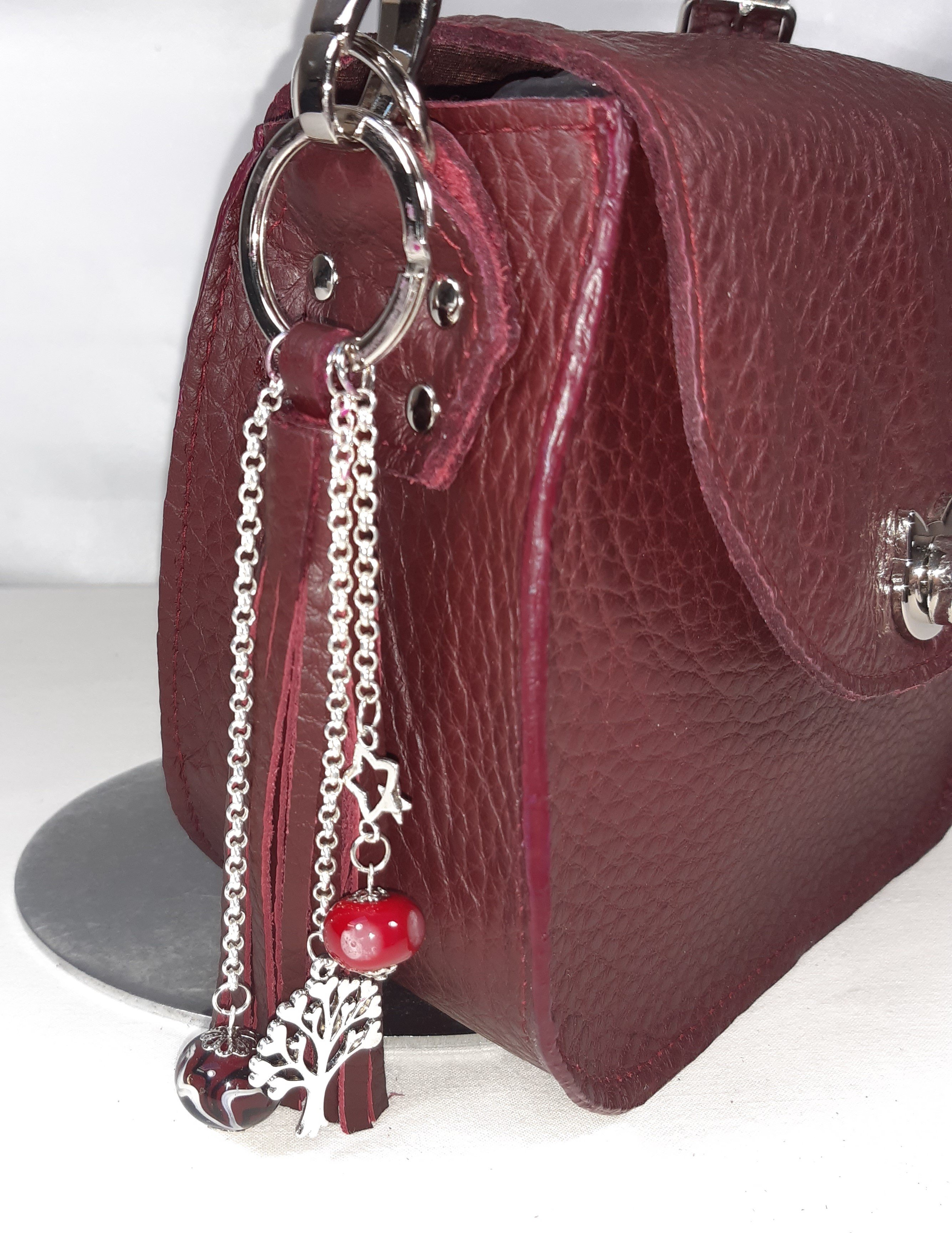 Bijou de sac, pompon cuir coloris bordeaux avec perles en verre filé.