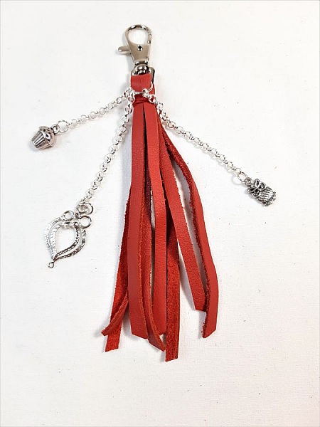 Bijou de sac pompon en cuir rouge avec charms argentés.
